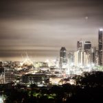 Elevated foggy night view of Brisbane city skyline from Bartley’s Hill with glowing lights and moody sky