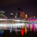 Brisbane city skyline at night featuring lit-up bridge and Treasury Casino with reflections on the Brisbane River