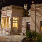 Heritage-style sandstone building illuminated at night with warm lighting and garden in foreground
