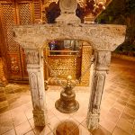 Bronze bell at the Nepal Peace Pagoda in South Bank, Brisbane, framed by carved timber and ornate architecture at night