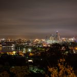 `Long exposure view of Brisbane city skyline at night with glowing lights and soft cloud cover, seen from an elevated lookout