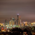 Long exposure night photo of Brisbane CBD skyline with illuminated buildings under a glowing sky, viewed from an elevated location