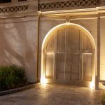 Elegant arched entryway of sandstone building illuminated at night with architectural lighting