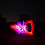 Sculptural red, pink, and blue light painting in front of a WWII radar bunker at night