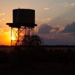 Silhouetted water tower at sunset with golden clouds in the background